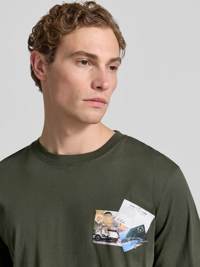 Männermodel trägt Regular Fit T-Shirt aus reiner Baumwolle von Tom Tailor in Optik: Unifarben mit Motiv-Print, Rundhals, Kurzarm, Nahaufnahme Oberkörper.