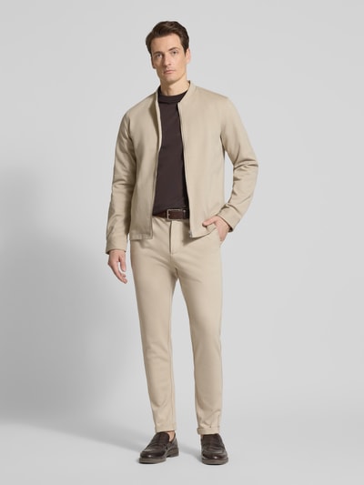 Männermodel trägt Cropped Hose mit Eingrifftaschen von Lindbergh in Beige, Material-Mix mit Viskose-Anteil, fein strukturiert, Ganzkörperansicht von vorne.