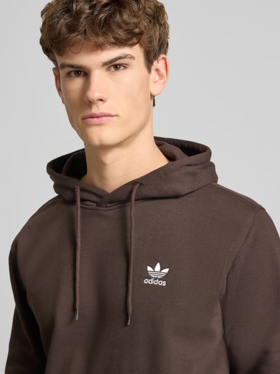 Männermodel trägt Hoodie mit Kapuze von adidas Originals in Braun, Baumwoll-Mix, lockerer Schnitt, Label-Stitching, Nahaufnahme Oberkörper