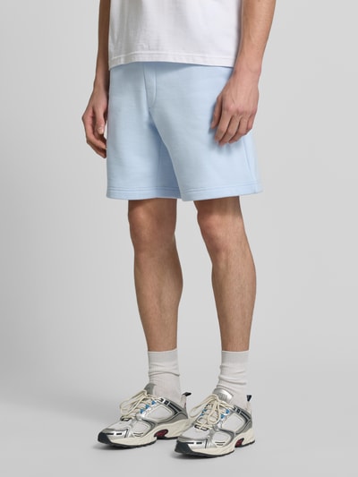 Männermodel trägt Relaxed Fit Sweatshorts aus Baumwoll-Mix von Lacoste in Hellblau, glatte Textur, Herren Sweatshorts, Ganzkörperansicht von vorne.