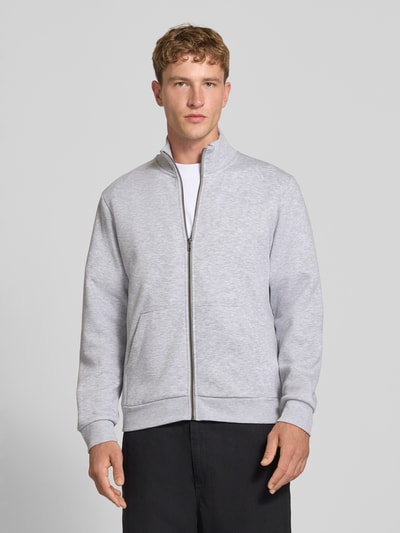 Männermodel trägt Regular Fit Sweatjacke mit Baumwoll-Anteil Modell 'Bradley' von JACK & JONES in Hellgrau, Ganzkörperansicht von vorne. Sweatjacke mit Stehkragen, Reißverschluss und geteilten Känguru-Taschen, Material-Mix, Rückenlänge 68 cm, Ärmellänge 66 cm.