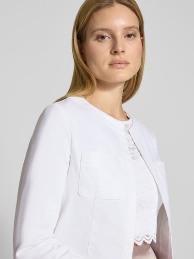 Modelka kobieca nosi Cropped Jacke mit Brusttaschen od SWING, mieszanka bawełny z dodatkiem streczu, krój krótki, otwarty fason, kieszenie na piersi, długość tyłu w rozmiarze 36: 44 cm, zbliżenie na górną część ciała.