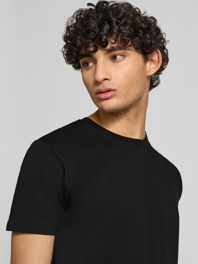 Männermodel trägt Herren T-Shirt mit Label-Patch Modell 'Camo' von Alpha Industries, schwarze Reine Baumwolle, Nahaufnahme Oberkörper.