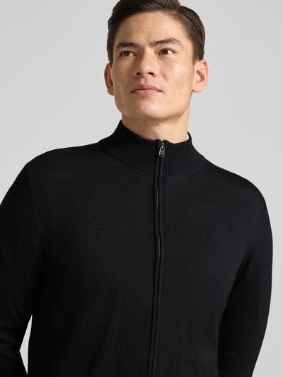 Männermodel trägt Cardigan mit Label-Detail Modell 'Balonso' von BOSS aus reiner Schurwolle im unifarbenen Design, Nahaufnahme Oberkörper.