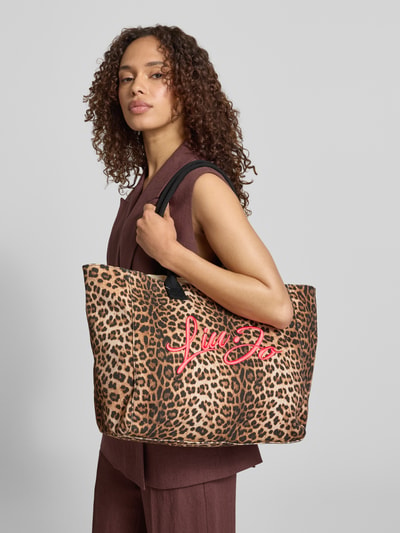 Frauenmodel trägt Shopper im Allover-Look mit Label-Stitching von Liu Jo White aus Reine Baumwolle, Hauptfach mit Reißverschluss, Ganzkörperansicht von vorne.