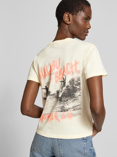 Frauenmodel trägt Regular Fit T-Shirt mit Logo-Detail von Anine Bing aus reiner Baumwolle in Creme mit Print, Rückenlänge 52 cm, Ganzkörperansicht Rückansicht.