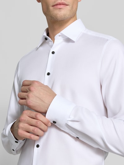 Męski model nosi Body Fit Businesshemd mit extra langem Arm od OLYMP, biała gładka tkanina, czarne guziki, zbliżenie na górę ciała, koszule biznesowe OLYMP Level 5.