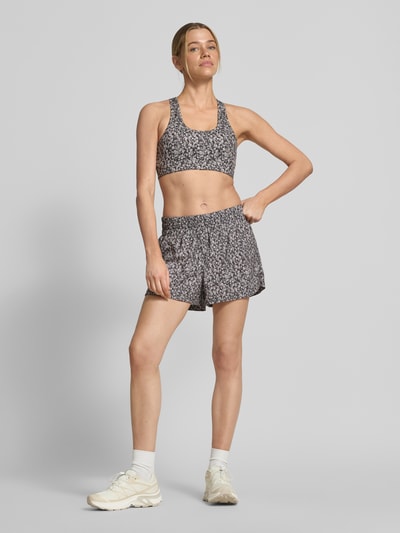 Frauenmodel trägt Running Shorts mit elastischem Bund Modell 'kallin' von VARLEY im Damen-Relaxed-Fit aus Material-Mix mit Stretch-Anteil, grafisches Allover-Muster mit kurzen Beinen, Bundweite bei Größe S 40 cm, Innenbeinlänge 8 cm. Ganzkörperansicht von vorne.