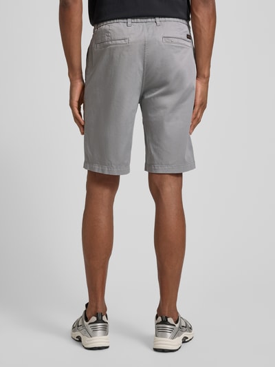 Männermodel trägt Tapered Chinoshorts aus Baumwoll-Mix von BOSS Orange in Unifarben, Materialverarbeitung: Twill, Ganzkörperansicht Rückansicht.