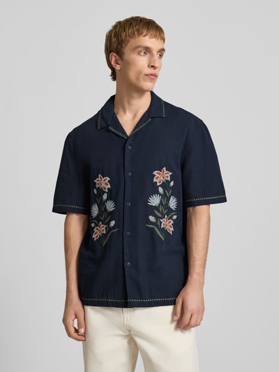 Männermodel trägt Relaxed Fit Freizeithemd mit Motiv-Stitching von REVIEW aus Baumwoll-Mix, dunkelblau mit Blumen, Knopfleiste, Reverskragen, Ganzkörperansicht von vorne. Rückenlänge bei Größe M: 72 cm, Schulterbreite: 45 cm, Ärmellänge: 30 cm.
