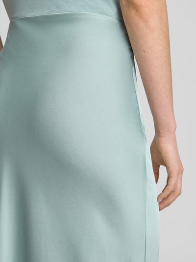 Kobieta nosi Maxirock aus Satin Modell 'VIELLETTE' od Vila, jasnomiętowy satynowy materiał, prosty krój, high waist, zbliżenie na biodra, Szerokość w rozmiarze 36: 35 cm, Długość całkowita: 94 cm, detal z boku