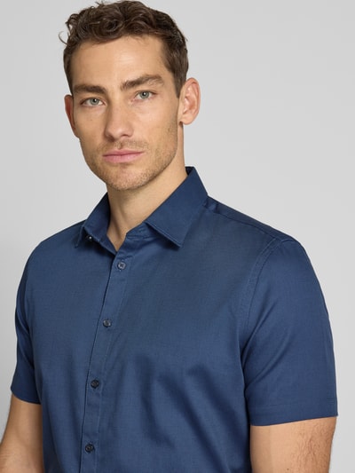 Männermodel trägt Slim Fit Business-Hemd aus Baumwolle mit Kentkragen von Jake*s, dunkelblau, Knopfleiste, Nahaufnahme Oberkörper.