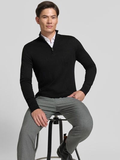 Männermodel trägt schwarzen Troyer mit Label-Applikation von MARKUP, Viskose-Mix, gerader Schnitt, Nahaufnahme Oberkörper.