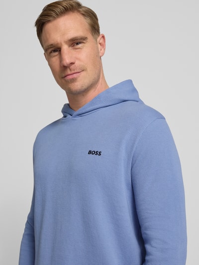 Männermodel trägt Comfort Fit Langarmshirt aus Baumwoll-Mix Modell 'WAFFLE' von BOSS in Hellblau, Piqué-Struktur, Nahaufnahme Oberkörper.