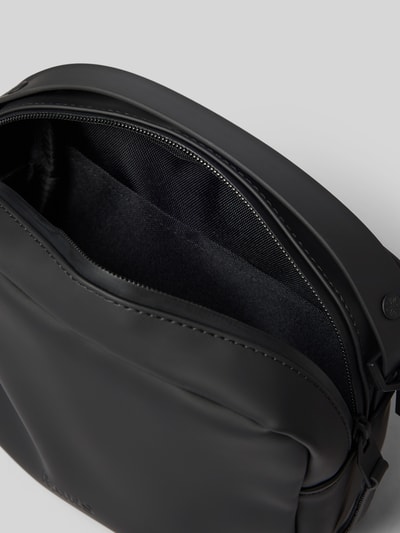 Produktfoto, Box Bag mit Logo-Detail von Rains, schwarze rechteckige Tasche mit Reißverschluss, glatte Oberfläche, Innenfach sichtbar