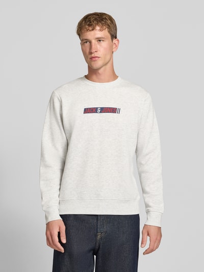Männermodel trägt Regular Fit Sweatshirt mit Baumwoll-Anteil Modell 'Munk' von JACK & JONES, hellgrau, Logo-Print, Ganzkörperansicht von vorne.
