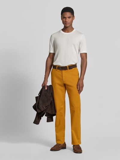 Męski model nosi Hose mit Gesäßtaschen od Christian Berg Men, bawełna z domieszką elastanu, krój slim fit, kolor musztardowy, szerokość w rozmiarze 50: 45 cm, długość nogawki wewnętrznej w rozmiarze 50: 80 cm, widok całej sylwetki z przodu.