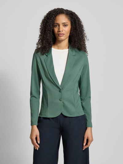 Frauenmodel trägt Slim Fit Blazer mit Viskose-Anteil Modell 'Nanni' von FREE/QUENT in grün, Reverskragen, Doppelknopfleiste, Ganzkörperansicht von vorne. Elastischer Material-Mix, schlichte Struktur, dezente Farbgebung.