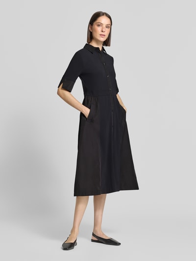Vrouwenmodel draagt Midikleid met Umlegekragen van Marc Cain, zwart, elastische materiaalmix, getailleerd, met steekzakken, knoopsluiting, 1/2-mouwen, ruglengte 120 cm, borstwijdte 46 cm, mouwlengte 32 cm, geheel lichaamsaanzicht van voren.