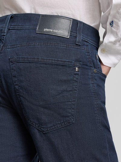 Männermodel trägt Jeansshorts mit Label-Detail von Pierre Cardin in Dunkelblau, Baumwoll-Mix mit Stretch-Anteil, Nahaufnahme Rückansicht, Regular-Fit, Eingrifftaschen, Umschlag, Bundweite 42 cm, Innenbeinlänge 26 cm in Größe 32.
