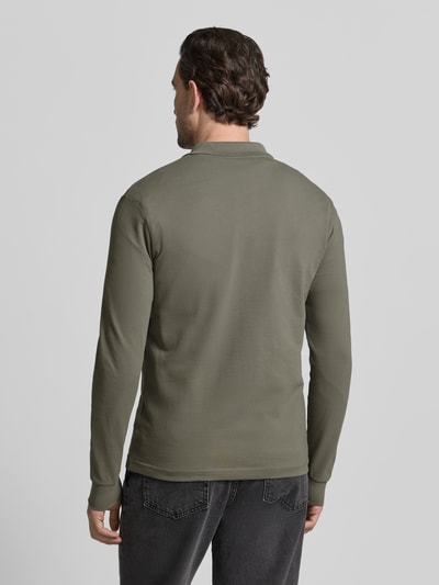Männermodel trägt Slim Fit Poloshirt aus Baumwoll-Mix Modell 'PASSERBY' von BOSS Orange in Olivgrün, unifarben, Ganzkörperansicht Rückansicht.