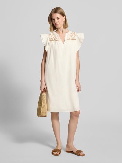 Frauenmodel trägt Relaxed Fit Minikleid mit Loch-Stickerei von ROBE LÉGÈRE in Creme, reine Baumwolle, Tunika-Ausschnitt, Ganzkörperansicht von vorne.