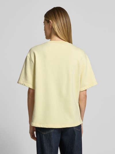 Frauenmodel trägt Sweatshirt mit 1/2-Arm und Rundhalsausschnitt von Rich & Royal, gelber Bio-Baumwoll-Mix mit Stretch-Anteil, Loose-Fit, seitliche Schlitze, Ganzkörperansicht Rückansicht.