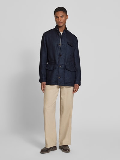 Męski model nosi Leinenjacke mit Stehkragen und Pattentaschen od bugatti, granatowy len, krój regular fit, listwa guzikowa, kieszenie z patką, długość tyłu w rozmiarze 50: 74 cm, szerokość ramion w rozmiarze 50: 46 cm, szerokość klatki piersiowej w rozmiarze 50: 55 cm, długość rękawów w rozmiarze 50: 64 cm, widok całościowy z przodu