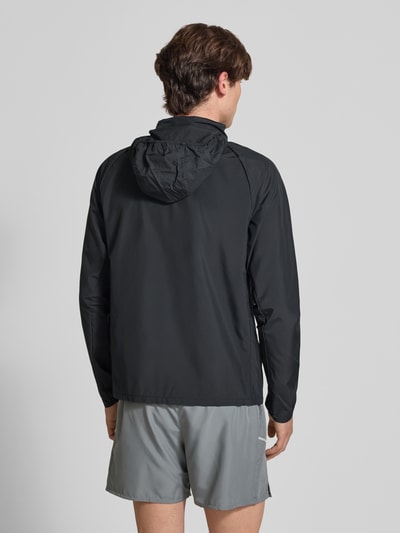 Männermodel trägt Regular Fit Jacke mit Stehkragen Modell 'Miler' von NIKE TRAINING in Schwarz, Rückenlänge 67 cm, Ärmel 64 cm, Logo-Print, Reißverschluss, Ganzkörperansicht Rückansicht.