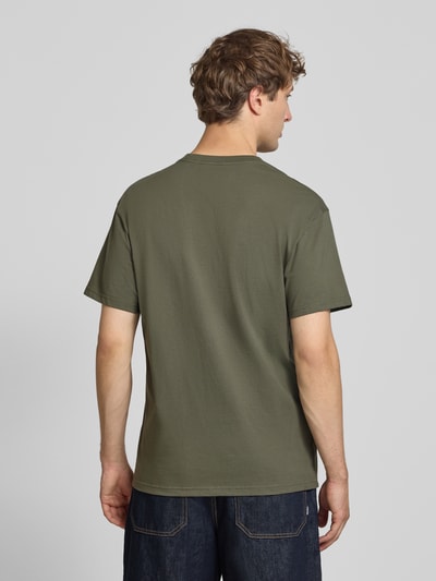 Männermodel trägt T-Shirt mit Label-Stitching und Rundhalsausschnitt von Carhartt Work In Progress, olivgrün, reine Baumwolle, Rückenlänge 72 cm, Ganzkörperansicht Rückansicht.