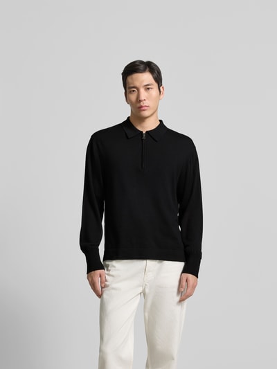 Männermodel trägt Pullover aus reiner Lanawolle von Officine Générale, schwarz, Regular Fit, Polo-Kragen, Ganzkörperansicht von vorne.
