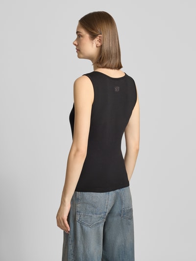 Frauenmodel trägt Top mit Rundhalsausschnitt Modell 'MOLLY' von Noisy May aus Baumwoll-Elasthan-Mix, Slim-Fit, Label-Detail, Rückenlänge 52 cm bei Größe S, dunkle Farbe, glatte Struktur, Ganzkörperansicht Rückansicht.