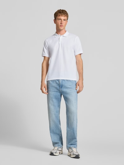 Männermodel trägt Regular Fit Poloshirt mit Baumwoll-Anteil Modell 'Austin' von JACK & JONES in Weiß mit Struktur-Muster, Ganzkörperansicht von vorne.
