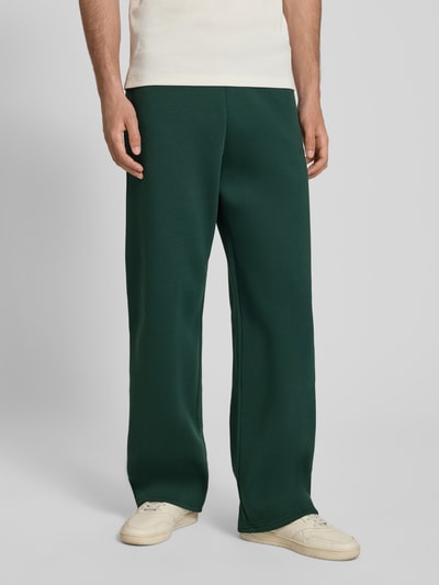 Männermodel trägt Regular Fit Sweatpants mit Gesäßtasche von REVIEW in Dunkelgrün, Baumwoll-Mix, elastischer Bund, Ganzkörperansicht von vorne.