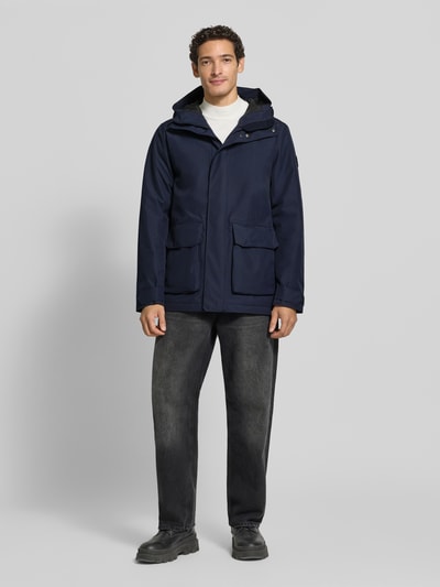 Männermodel trägt Regular Fit Jacke mit aufgesetzten Taschen Modell 'Liam' von Didriksons in Dunkelblau, Ganzkörperansicht von vorne, Herren Jacke, Kapuze, Rückenlänge 79 cm, Schulterbreite 44 cm, Brustweite 45 cm, Ärmellänge 70 cm.