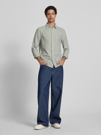 Männermodel trägt Regular Fit Freizeithemd aus Leinen-Baumwoll-Mix von Tommy Jeans, Mehrfarbig, Gestreift, Logo-Schriftzug, Ganzkörperansicht von vorne.