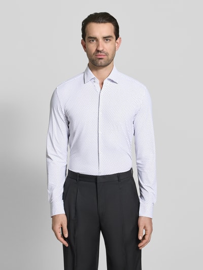 Männermodel trägt Slim Fit Businesshemd mit Kentkragen Modell 'KENNO' von HUGO, efekt: wzór na całej powierzchni, krój slim fit, kołnierzyk typu kent, jednorzędowa listwa guzikowa, wyhaftowane logo, pas na plecach, długi rękaw, zakończenie: zaokrąglony, mankiet zapinany na jeden guzik; widok: całe ciało z przodu