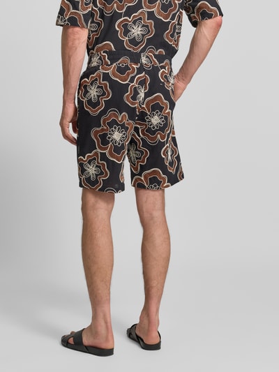 Mężczyzna nosi Straight Fit Shorts mit floralem Allover-Stitching von Antony Morato, czarna bawełna, elastyczny pas, krój straight fit, wzór kwiatowy, tylna kieszeń, Szerokość w rozmiarze 50: 45 cm, długość wewnętrzna nogawki: 22 cm, całkowity widok z tyłu.