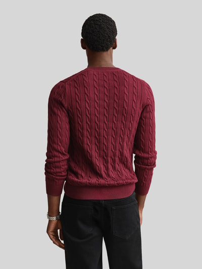 Männermodel trägt Regular Fit Pullover aus reiner Baumwolle von GANT in Dunkelrot mit Zopfmuster, Herren, Ganzkörperansicht Rückansicht.
