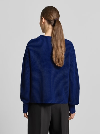 Frauenmodel trägt Strickpullover mit Stehkragen Modell 'TELLINA' von Someday in Blau, lockerer Schnitt, gerippte Textur, Ganzkörperansicht Rückansicht.