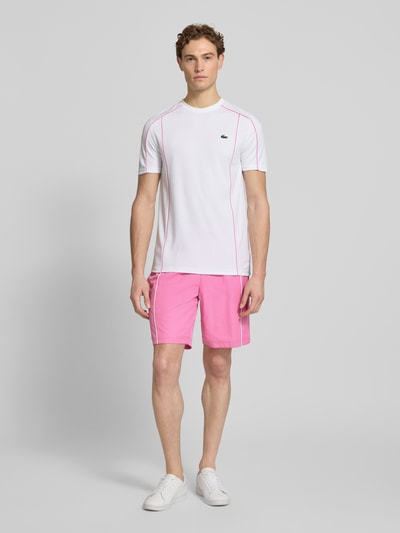 Männermodel trägt Regular Fit Sport-Shorts mit weichem Innenstoff von Lacoste Sport in Pink mit feinem Strukturmuster, Ganzkörperansicht von vorne.