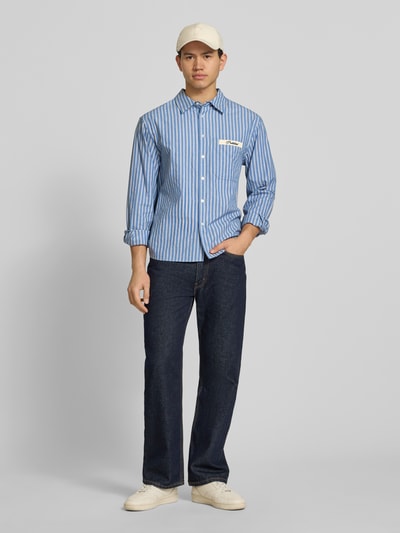 Männermodel trägt Regular Fit Freizeithemd mit Kentkragen Modell 'Drift' von PROHIBITED in Blau gestreift aus reiner Baumwolle, Ganzkörperansicht von vorne.