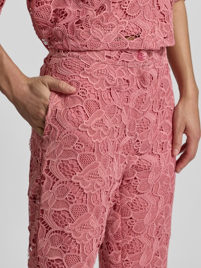 Vrouwenmodel draagt Stoffen broek uit kant met steekzakken van Jake*s collectie in roze, straight fit, knoop- en ritssluiting, detailopname heup en bovenbeen.