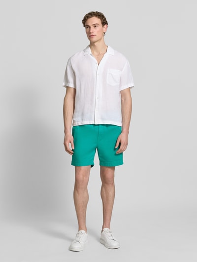 Männermodel trägt Regular Fit Shorts mit elastischem Bund Modell 'SUNFADED' von Gant in Grün aus reiner Baumwolle, Ganzkörperansicht von vorne.