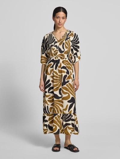 Frauenmodel trägt Midikleid aus Viskose mit Smok-Details Modell 'FELDI' von Soyaconcept, creme-braun-schwarzes Muster, taillierter Schnitt, Ganzkörperansicht von vorne.
