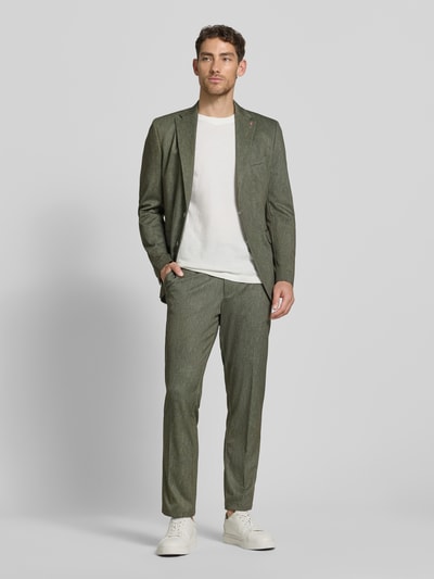 Męski model nosi Regular Fit Sakko mit Viskose-Anteil Modell 'Calvin' od CG - Club of Gents, zielony, gładka tekstura, krój regular fit, kieszeń na piersi, logo, patki, zapięcie na 2 guziki, długość pleców w rozmiarze 50: 74 cm, szerokość ramion w rozmiarze 50: 45 cm, długość rękawa w rozmiarze 50: 65 cm, zdjęcie całej sylwetki z przodu.
