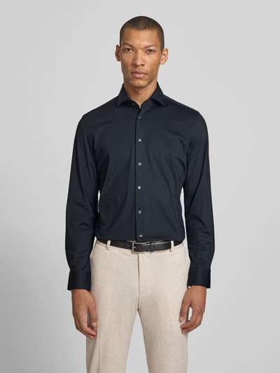 Männermodel trägt Slim Fit Business-Hemd mit Haifischkragen von SEIDENSTICKER, dunkelblau, glatte Struktur, Material-Mix mit Stretch-Anteil, Knopfleiste, Ganzkörperansicht von vorne. Rückenlänge 76 cm, Schulterbreite 43 cm, Ärmellänge 63 cm bei Größe 40.