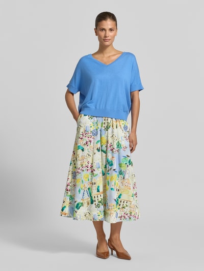 Frauenmodel trägt Strickshirt aus Viskose-Mix mit V-Ausschnitt von Milano Italy in Hellblau, kombiniert zu buntem Rock, Ganzkörperansicht von vorne. Regular Fit, 1/2-Arm, Kaschmir-Anteil, Rückenlänge 54 cm, Ärmellänge 34 cm.