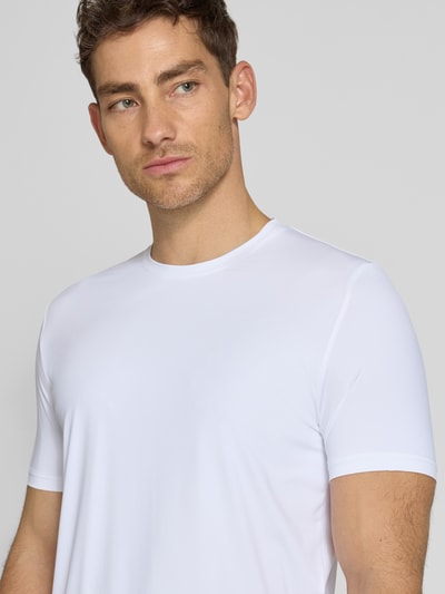 Männermodel trägt weißes T-Shirt mit Rundhalsausschnitt Modell 'TESSUTO' von MARKUP im Modern Fit, glatte Textur, Nahaufnahme Oberkörper. Nylon-Mix mit Stretch, Label-Detail, Rückenlänge bei Größe M 67 cm.