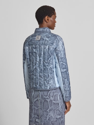 Frauenmodel trägt Regular Fit Jacke in Stepp-Optik mit Stehkragen von Marc Cain, Allover-Schlangen-Print, Struktur, Rückansicht.